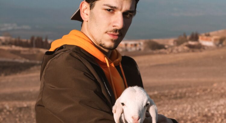 a young farmer holds a baby lamb